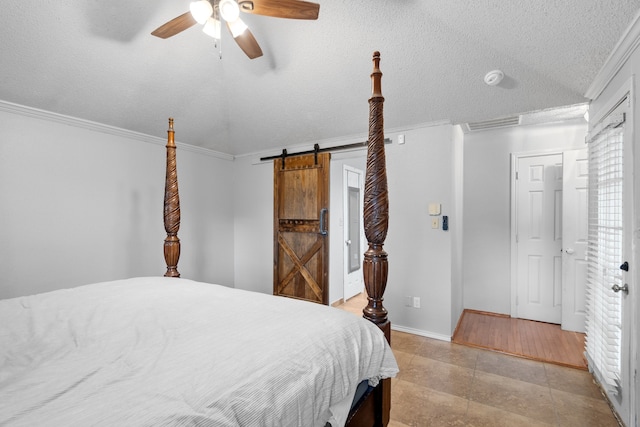 bedroom with a barn door, ceiling fan, crown molding, and a textured ceiling