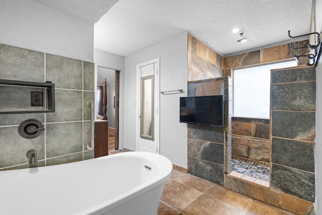 bathroom with a textured ceiling, tile walls, and shower with separate bathtub