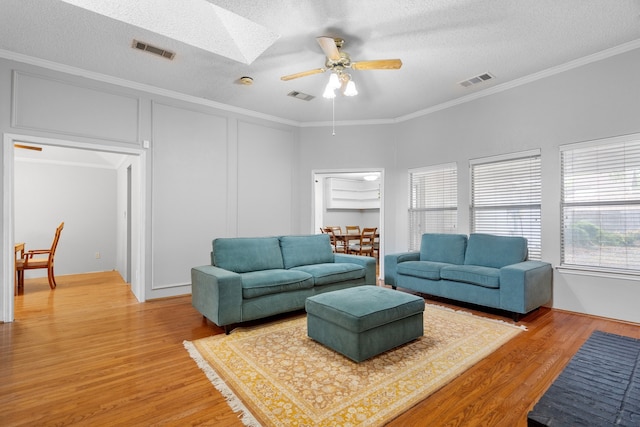 living room with plenty of natural light, hardwood / wood-style floors, a skylight, and ceiling fan