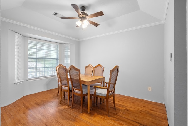 dining space featuring a raised ceiling, ceiling fan, ornamental molding, and light hardwood / wood-style floors