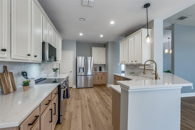 kitchen with backsplash, stainless steel appliances, decorative light fixtures, white cabinets, and light hardwood / wood-style floors