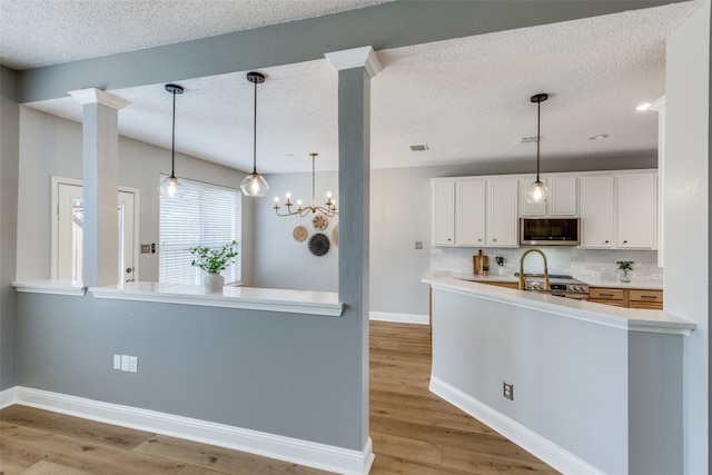 kitchen featuring light hardwood / wood-style flooring, decorative backsplash, white cabinetry, kitchen peninsula, and stainless steel appliances