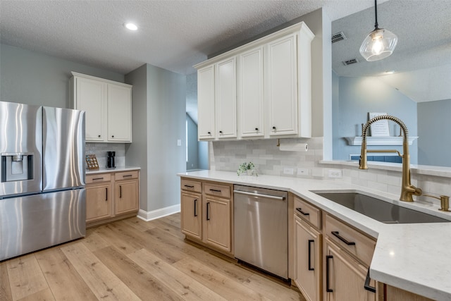 kitchen with light brown cabinetry, tasteful backsplash, stainless steel appliances, decorative light fixtures, and light hardwood / wood-style floors