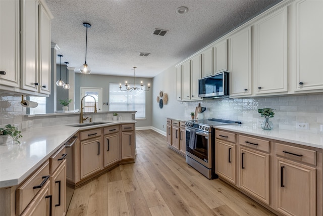 kitchen featuring pendant lighting, light wood-type flooring, sink, and appliances with stainless steel finishes