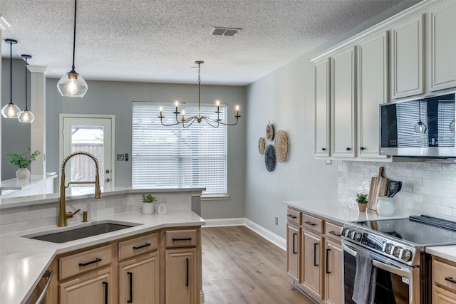 kitchen with stainless steel appliances, light hardwood / wood-style flooring, hanging light fixtures, and sink