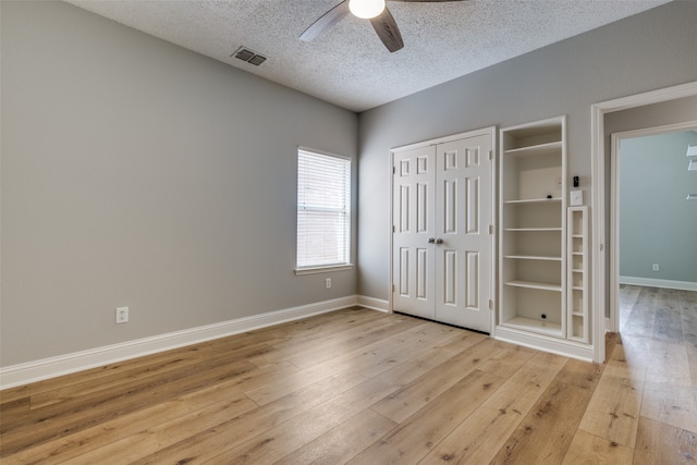 unfurnished bedroom with ceiling fan, light wood-type flooring, and a textured ceiling