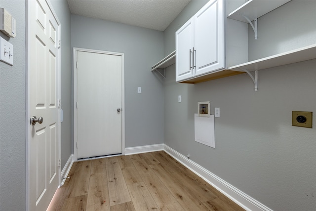 laundry room with cabinets, hookup for an electric dryer, light hardwood / wood-style flooring, hookup for a washing machine, and a textured ceiling