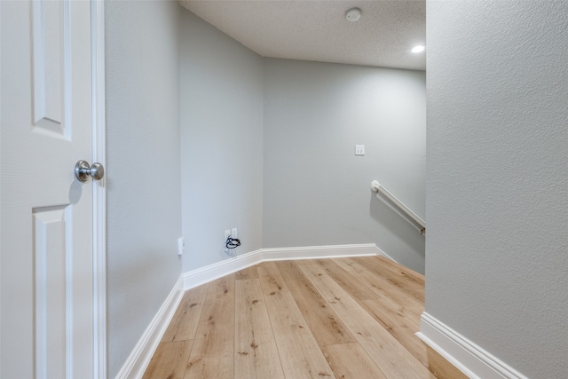 laundry area with a textured ceiling, light hardwood / wood-style flooring, and electric dryer hookup