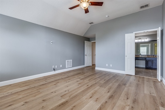 unfurnished bedroom with ceiling fan, light hardwood / wood-style floors, lofted ceiling, and connected bathroom