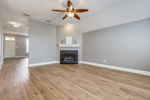 unfurnished living room featuring a textured ceiling, vaulted ceiling, ceiling fan, a fireplace, and light hardwood / wood-style floors