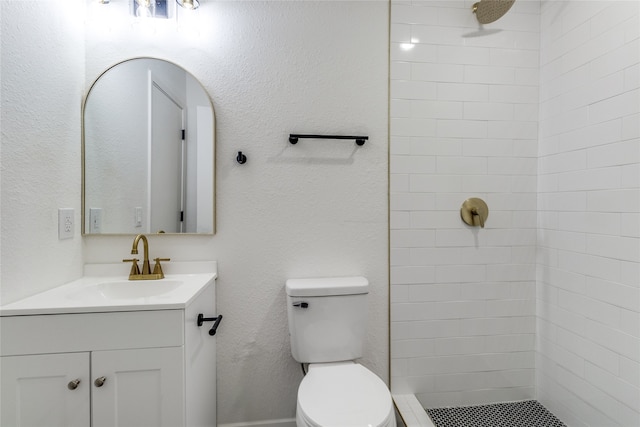 bathroom with tiled shower, vanity, and toilet