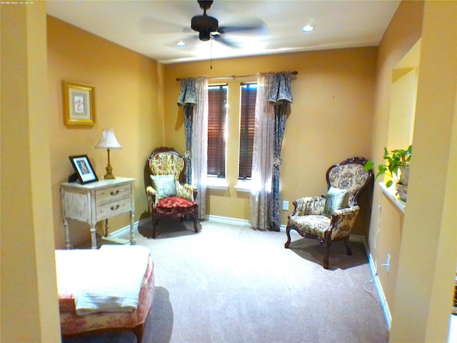 living area with carpet and ceiling fan