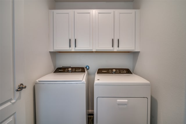 clothes washing area featuring cabinets and separate washer and dryer