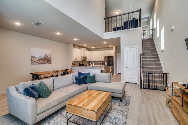 living room with a towering ceiling and light hardwood / wood-style floors