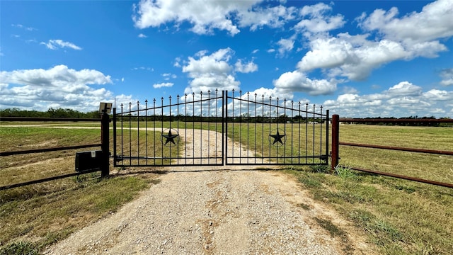 view of gate featuring a lawn and a rural view