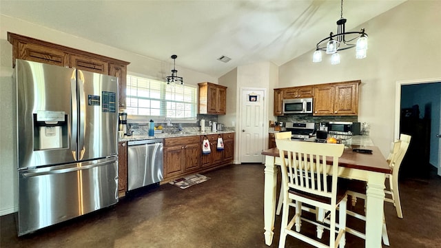 kitchen featuring pendant lighting, lofted ceiling, stainless steel appliances, and tasteful backsplash