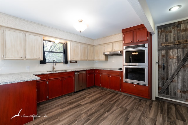 kitchen featuring dark hardwood / wood-style flooring, stainless steel appliances, a barn door, and sink