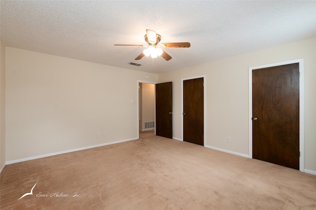 unfurnished bedroom featuring ceiling fan, light carpet, and a textured ceiling