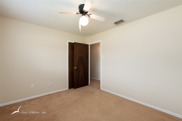 unfurnished room featuring a textured ceiling, light colored carpet, and ceiling fan