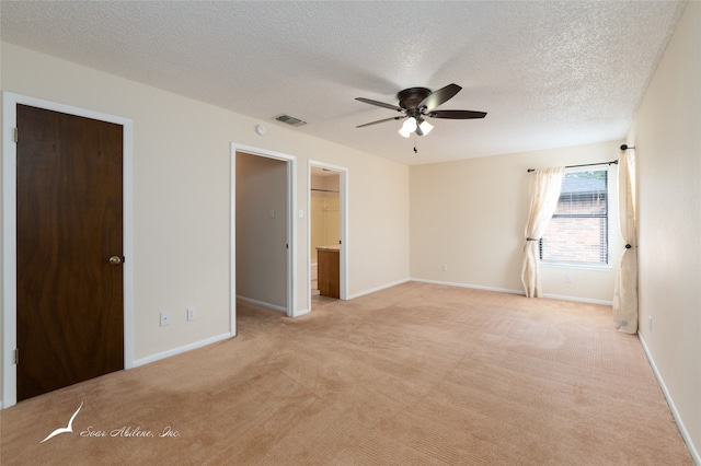 unfurnished bedroom featuring ensuite bath, ceiling fan, light colored carpet, a textured ceiling, and a closet