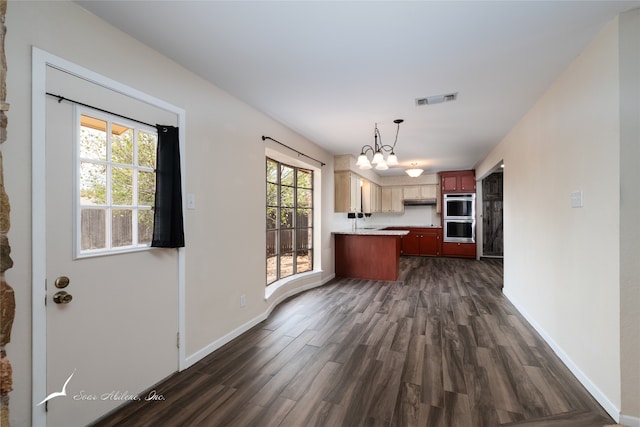 kitchen with double oven, dark wood-type flooring, decorative light fixtures, and a notable chandelier