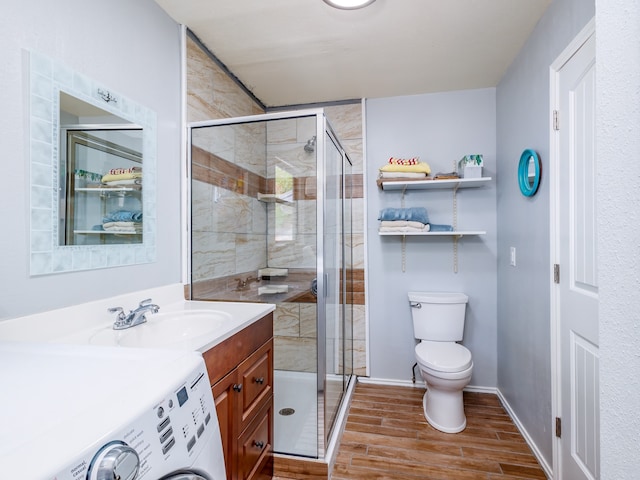 bathroom featuring a shower with door, toilet, wood-type flooring, washer / dryer, and vanity