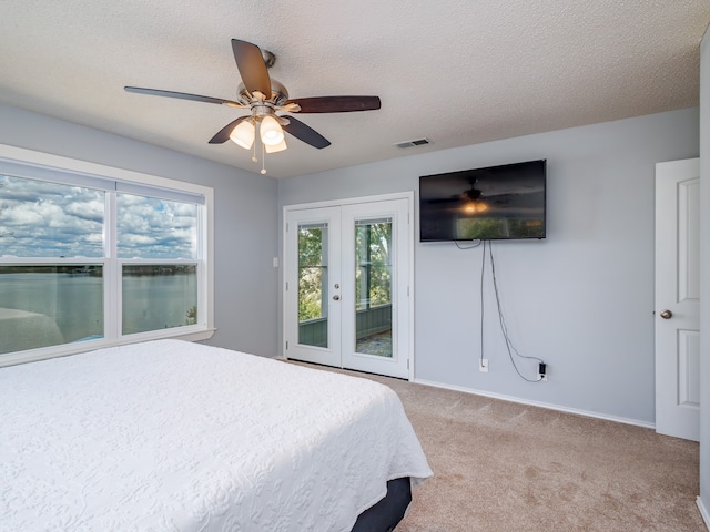 bedroom featuring a textured ceiling, french doors, access to exterior, carpet flooring, and ceiling fan