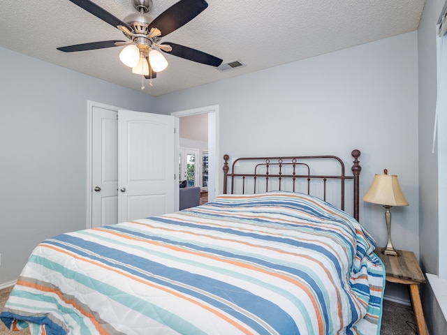 carpeted bedroom with a textured ceiling, ceiling fan, and a closet