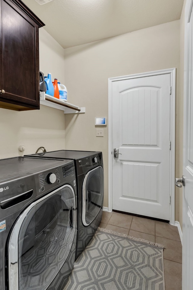 laundry room with washer and clothes dryer, light tile patterned floors, and cabinets