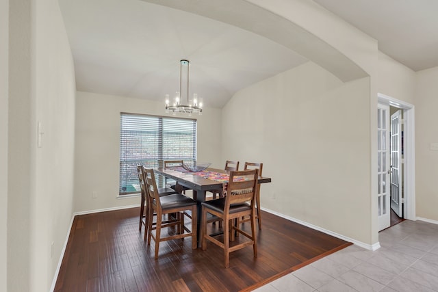 dining room featuring vaulted ceiling, an inviting chandelier, and light hardwood / wood-style floors