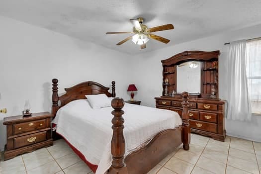 tiled bedroom featuring ceiling fan