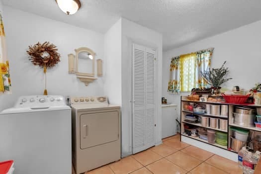 laundry area with light tile patterned floors, a textured ceiling, and separate washer and dryer