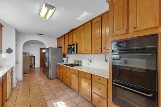 kitchen featuring appliances with stainless steel finishes, light tile patterned floors, and a textured ceiling