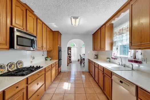 kitchen with light tile patterned floors, dishwasher, sink, gas cooktop, and a textured ceiling