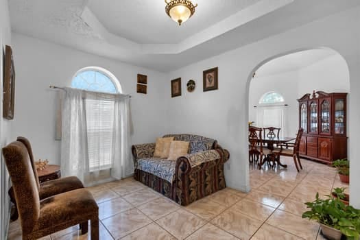 living area with a raised ceiling and light tile patterned flooring