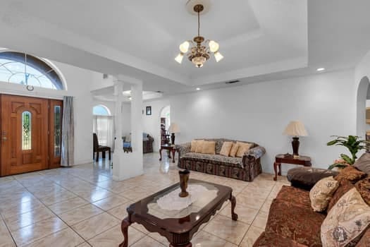 living room featuring a raised ceiling and an inviting chandelier