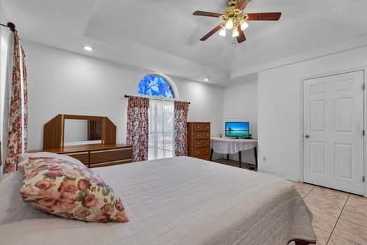 tiled bedroom featuring a tray ceiling and ceiling fan