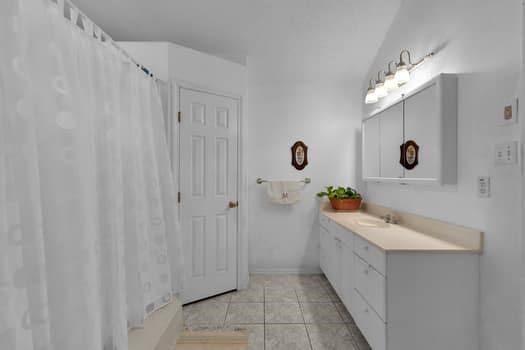 bathroom with tile patterned flooring, walk in shower, and vanity