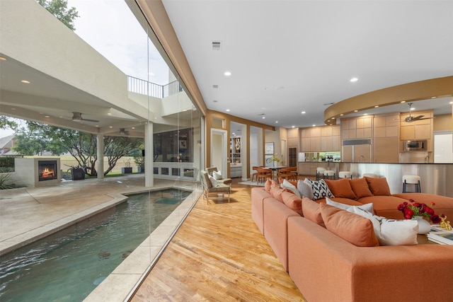 living room with a wealth of natural light, light hardwood / wood-style flooring, and ceiling fan