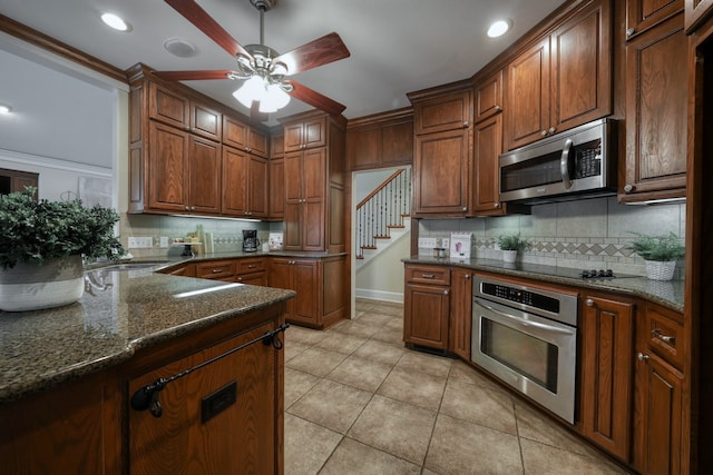 kitchen featuring light tile patterned floors, crown molding, stainless steel appliances, ceiling fan, and dark stone counters