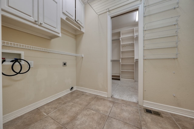 clothes washing area featuring washer hookup, cabinets, light tile patterned floors, and hookup for an electric dryer