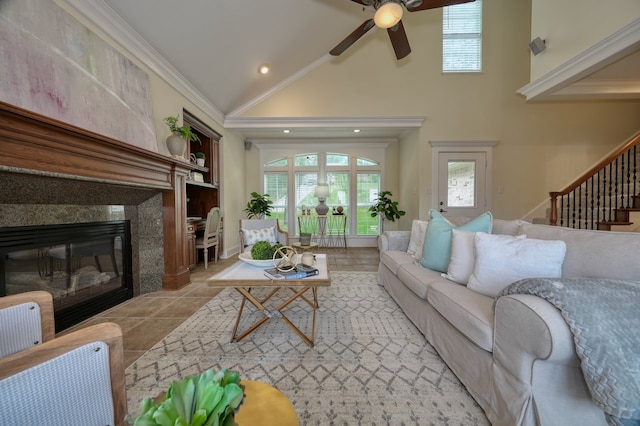 tiled living room featuring a premium fireplace, ceiling fan, ornamental molding, and high vaulted ceiling