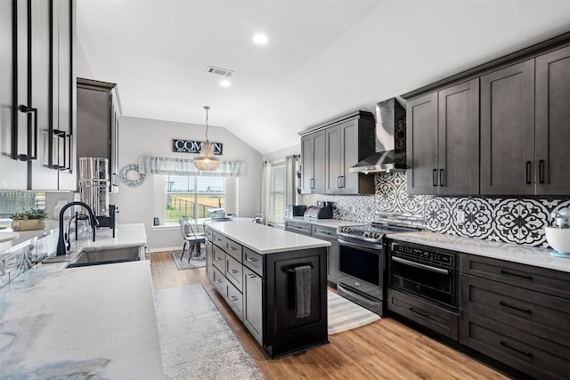 kitchen with sink, wall chimney exhaust hood, light hardwood / wood-style floors, vaulted ceiling, and stainless steel electric stove