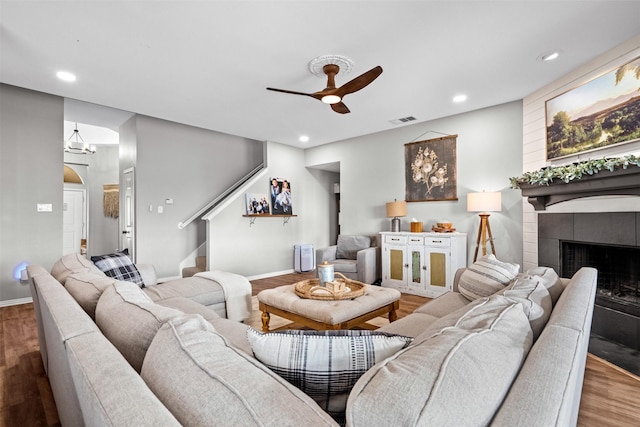 living room with hardwood / wood-style floors, ceiling fan, and a tiled fireplace