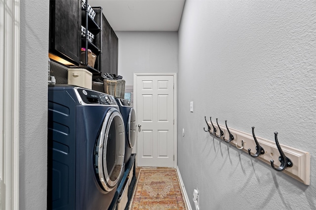 washroom featuring cabinets and washer and clothes dryer