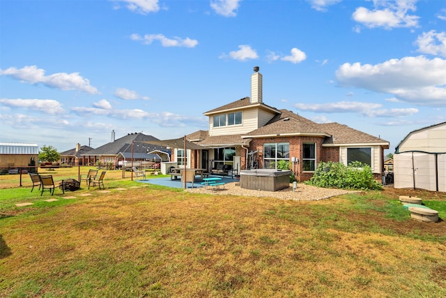 back of house featuring a lawn, a patio area, a hot tub, and a storage shed