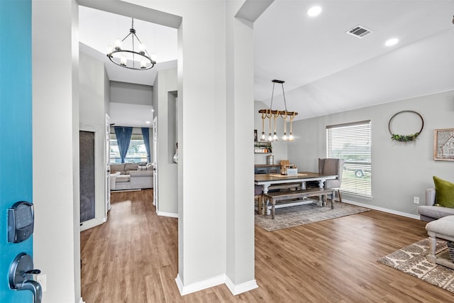 hallway featuring lofted ceiling, wood-type flooring, and a chandelier