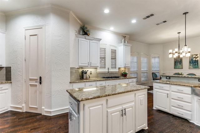 kitchen featuring crown molding, light stone countertops, a center island, and white cabinets