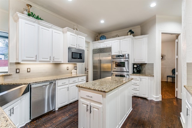 kitchen featuring built in appliances, light stone counters, white cabinetry, and a center island