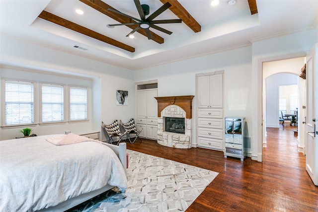 bedroom featuring dark hardwood / wood-style flooring, a tray ceiling, and a fireplace